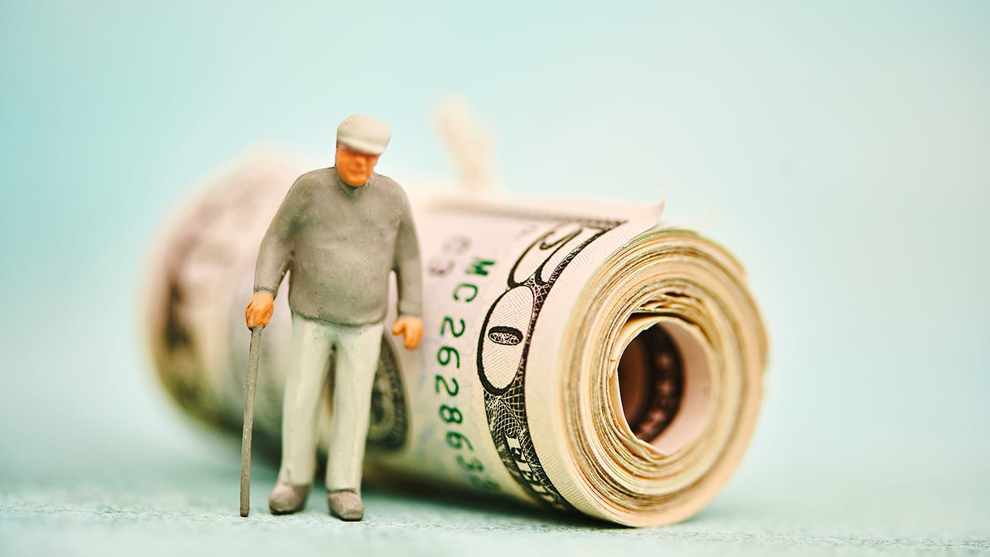 figure of old man in front of a roll of money